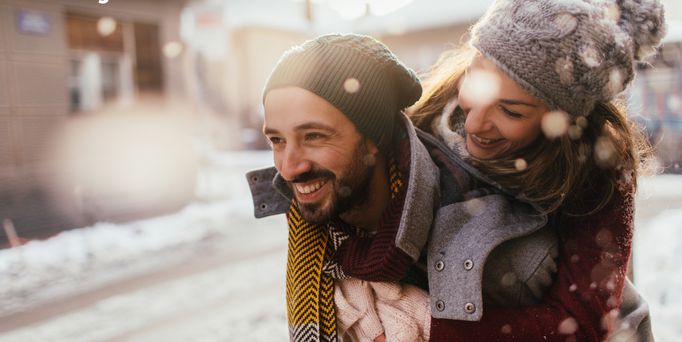 Ein junges Paar lacht glücklich und ist winterlich angezogen