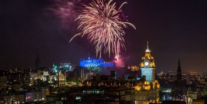 Die Skyline von Edinburgh unter schwarzem Nachthimmel mit Feuerwerk.