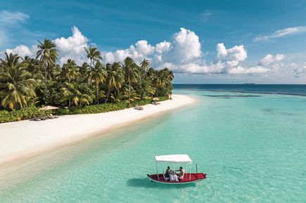 An einem tropischen Strand fährt ein Boot mit Sonnendach.