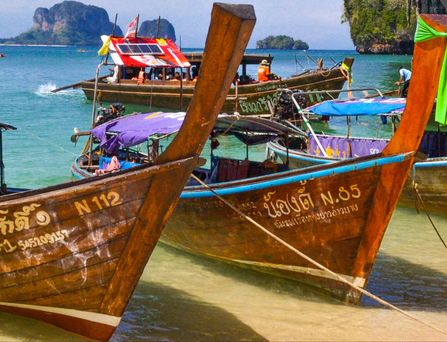 Reiseziele weltweit: thailändische Longtailboote in einer Bucht.