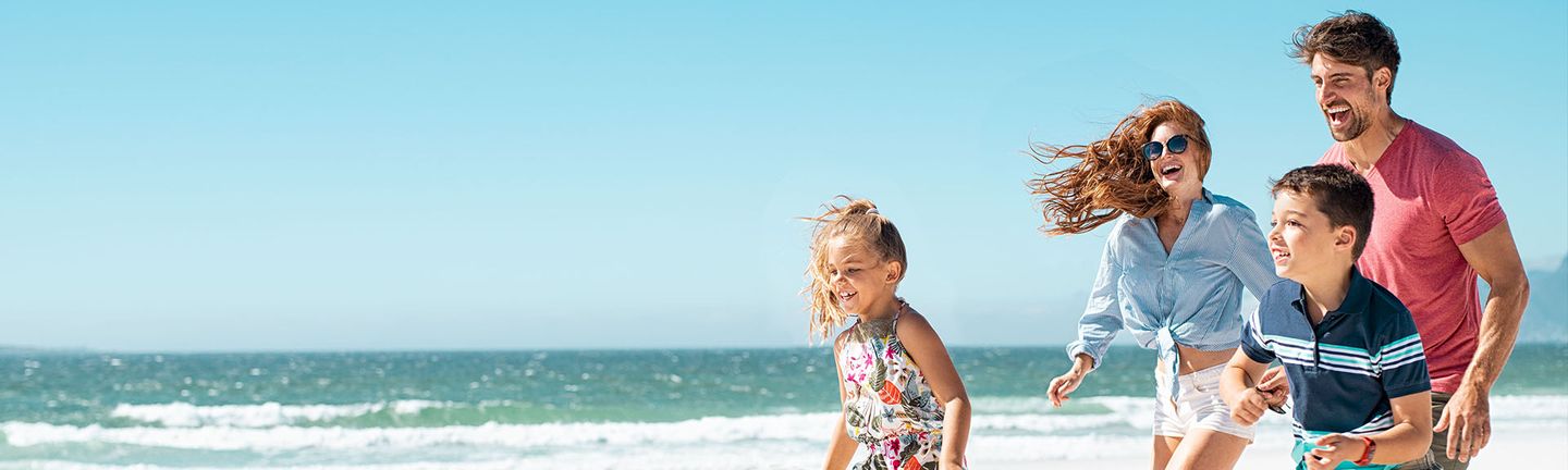 Eine glückliche Familie läuft lachend am Strand entlang