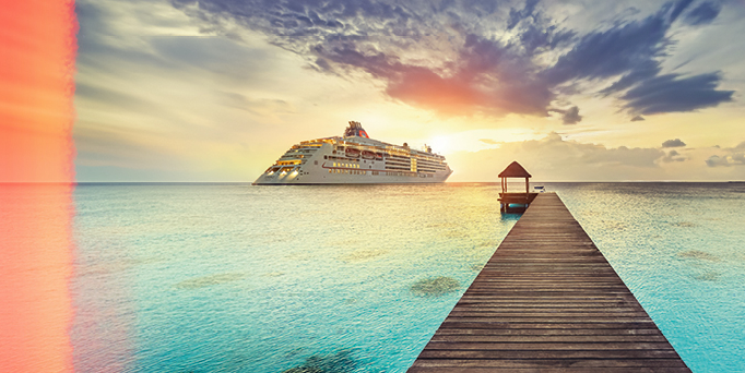 Kreuzfahrtschiff auf ruhigem Meer bei Sonnenuntergang, rechts ein Steg mit kleinem Pavillon, oben rechts Logo von Hapag-Lloyd Cruises.