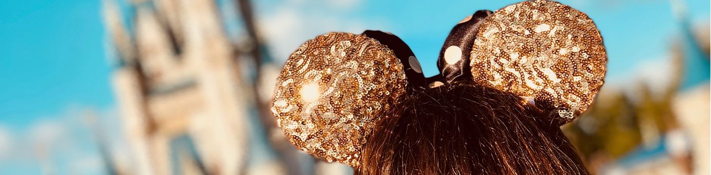 Der Kopf eines braunhaarigen Mädchens mit gold-glitzernden Minimouse Ohren.