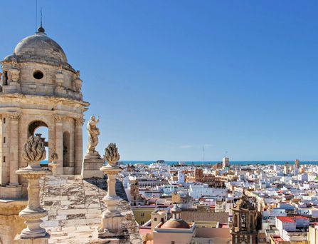 Eine wunderschöne historische Stadtskyline erstreckt sich unter blauem Himmel bis hin zum tiefblauen Meer am Horizont.