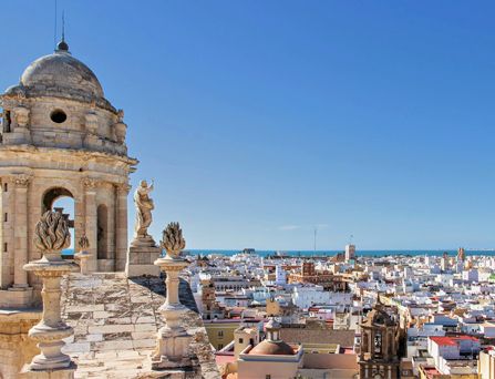 Eine wunderschöne historische Stadtskyline erstreckt sich unter blauem Himmel bis hin zum tiefblauen Meer am Horizont.
