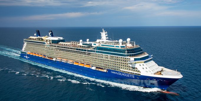 Ein weiß-blaues Kreuzfahrtschiff auf dem tiefblauen Meer.