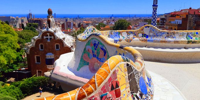 Ausschnitt aus dem Park Güell in Barcelona: Bunte, schlangenlinienförmige Mauern und skurile Hausdächer.