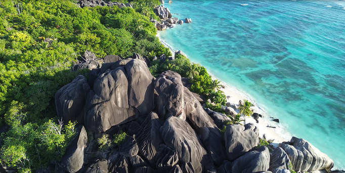 Warmer Winterurlaub: Ein weißer Strand am türkis-blauen Meer mit riesigen Steinen