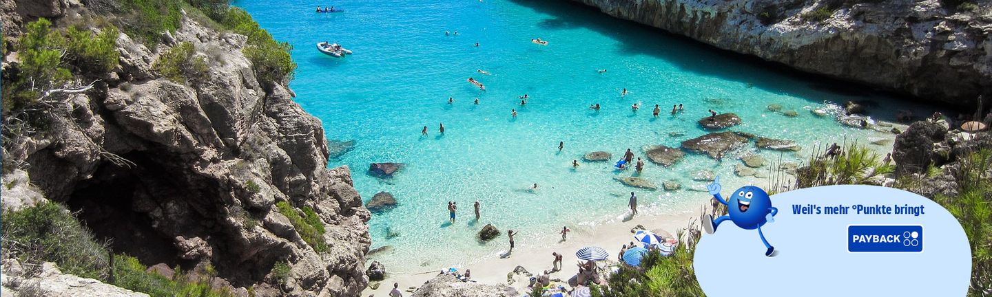 Eine Bucht mit türkisem Wasser und weißem Sandstrand..