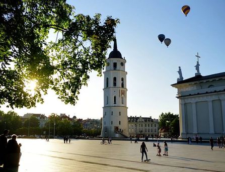 Ein historischer Turm an einem großen, recht leeren Platz und Heißluftballons am Himmel