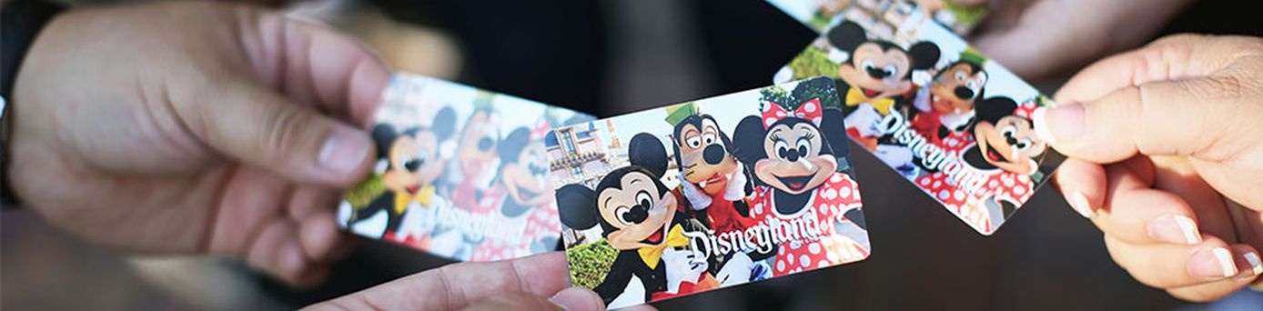 Mehrere Hände halten Disneyland-Tickets auf denen Mickey-,Minimouse sowie Goofy zu sehen sind.