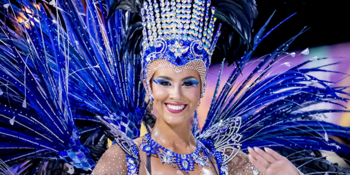 Großes Kreuzfahrtschiff auf ruhigem Meer vor einer Küstenstadt mit Hügeln im Hintergrund