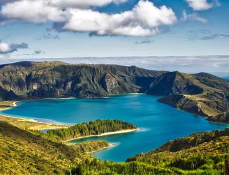 Eine grüne Berglandschaft, die einen tiefblauen See umschließt.