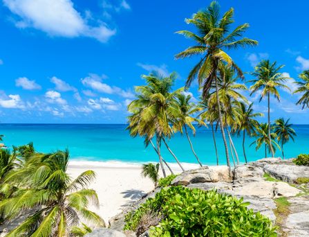 Ein mediteranes Dorf mit hübschen Häusern liegt direkt am türkis-blauen Meer, mit Bergen im Hintergrund.