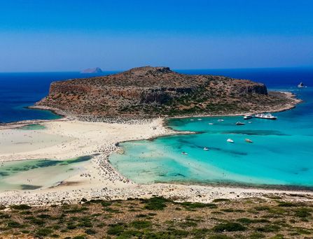 Eine karge, sandige Halbinsel, durch weißen Sandstrand verbunden mit dem Festland am türkis-blauen Meer.
