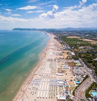 An einem weißen Sandstrand mit türkis-blauem Wasser steht eine krumm gebogene Kokospalme.