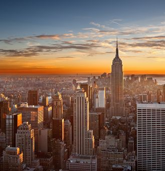 Die Skyline von New York unter dem dämmernden, orangenen Himmel.