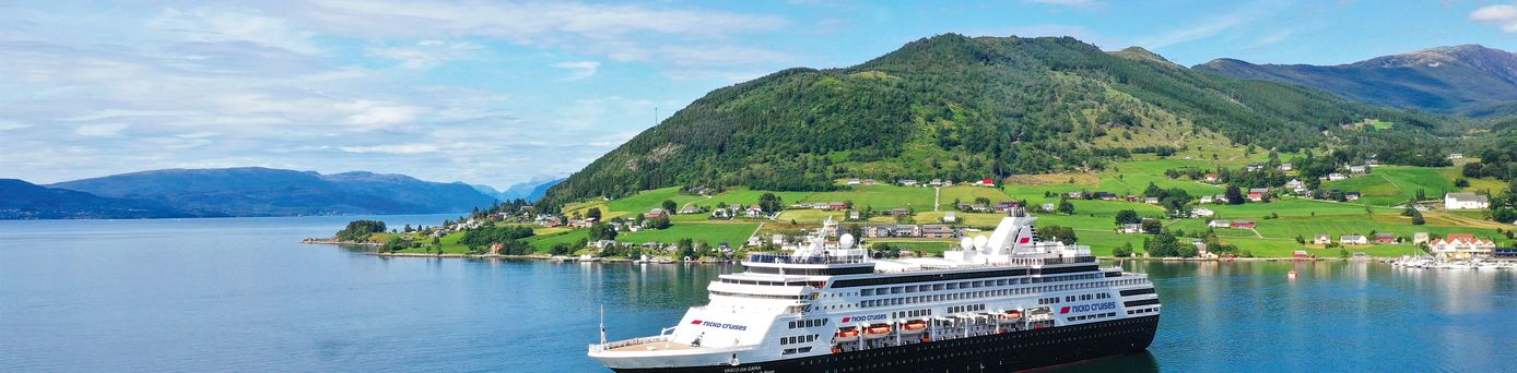 Das Schiff VASCO DA GAMA gleitet auf dem glatten Wasser dahin. Im Hintergrund eine grüne hügelige Landschaft.