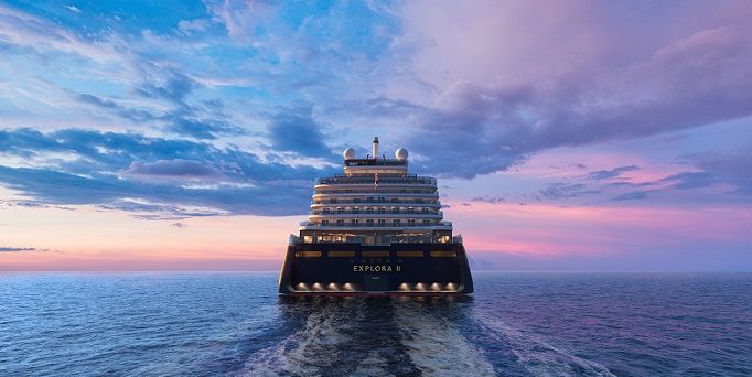 Das blau-weiße Kreuzfahrtschiff "Mein Schiff 4" gleitet durch das dunkle Meer entlang eines steilen Felsens mit Wasserfall.