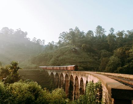 Ein Zug fährt über die 9-arch-bridge in Ella, Sri Lanka. Die Umgebung ist grüner Regenwald