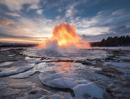 Aus einer vereisten Krustenlandschaft stößt explosionsartig Wasser empor.