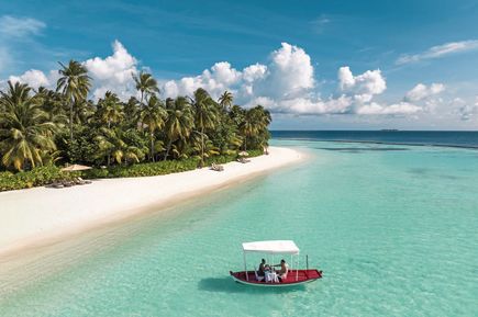 An einem tropischen Strand fährt ein Boot mit Sonnendach.