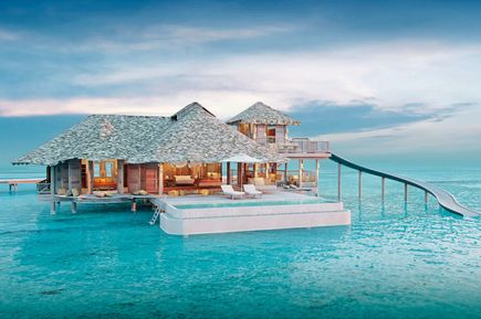 Ein Wasserbungalow auf türkis-blauem Wasser.
