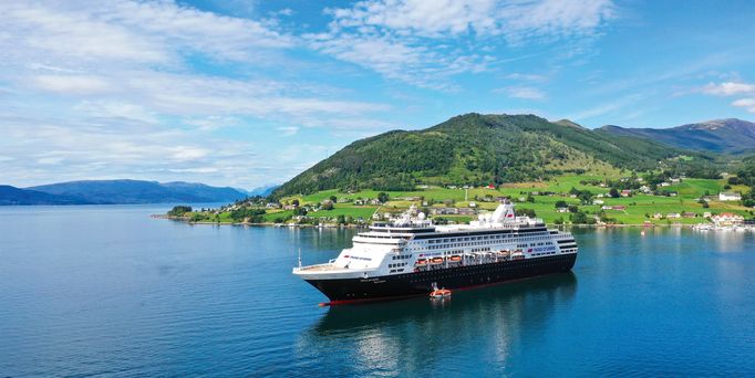 Das Schiff VASCO DA GAMA gleitet auf dem glatten Wasser dahin. Im Hintergrund eine grüne hügelige Landschaft.