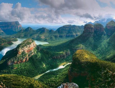 Belebter Platz mit mehreren Palmen, einem Brunnen und umliegenden historischen Gebäuden unter blauem Himmel.
