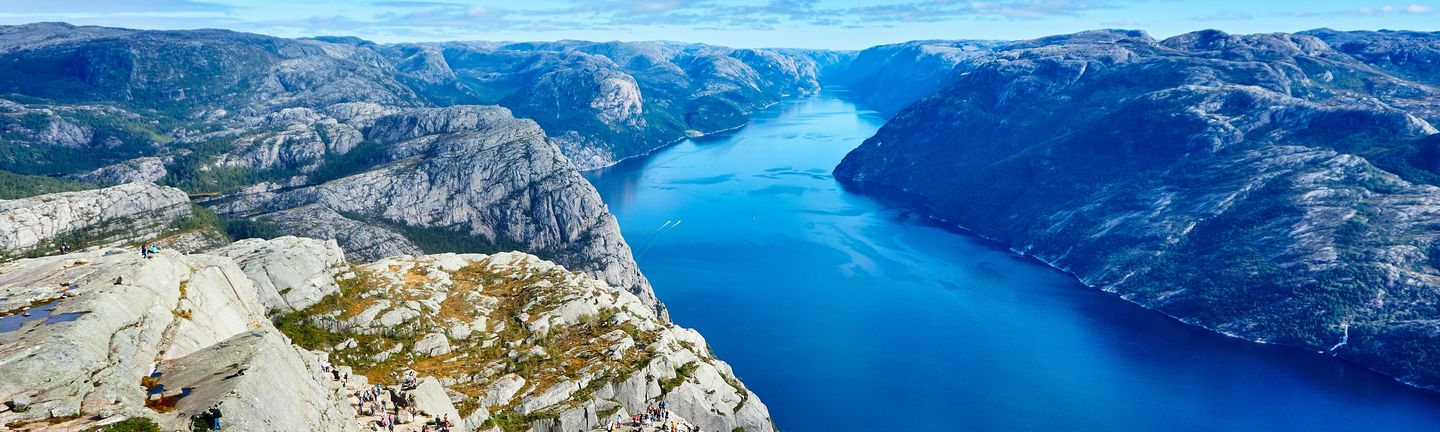 Ein tiefblauer Fjord zwischen steinigen, rauen Felsen.
