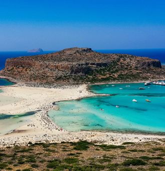 Eine irre, trockene Sand und Dünenlandschaft geht in das teils helltürkise, teils dunkelblaue Meer über.