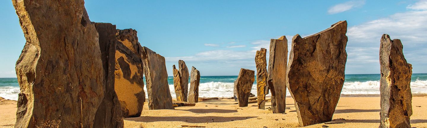 Portugal: Bizarre Felsen ragen aus einem goldenen Strand empor.