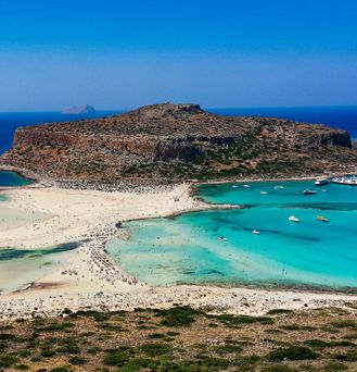 Eine irre, trockene Sand und Dünenlandschaft geht in das teils helltürkise, teils dunkelblaue Meer über.