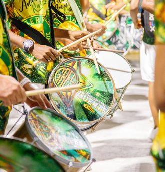 Nahaufnahme von brasilianischen Trommlern, welche in grün, gelb gekleidet sind.