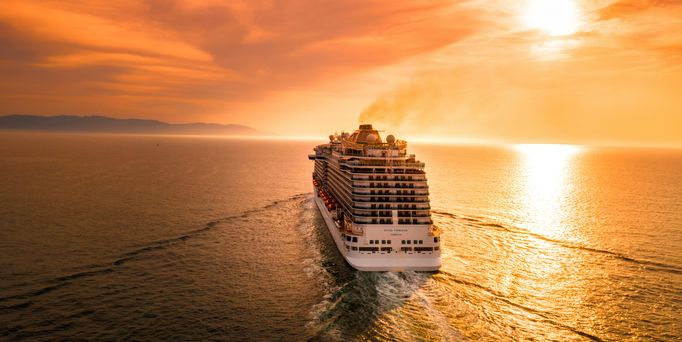 Offenes Meer im gold-orangenen Sonnenuntergang. Dem Horizont entgegen schwimmt ein riesiges Kreuzfahrtschiff drum herum das weite Nichts.