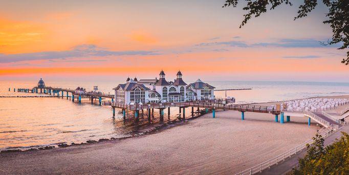 Reisetrends 2026: Ein Steg mit einem Haus am Strand mit Sonnenuntergang