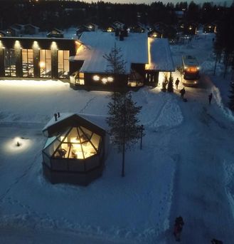 Außergewöhnliche Hotels: Luftaufnahme von beleuchteten Hütten mit Glasdach