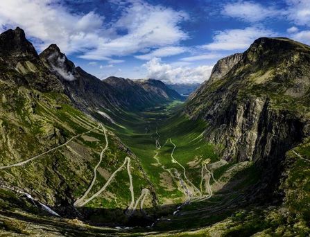 Eine grüne, tiefe Berglandschaft mit zick-zack-förmigen Straßen