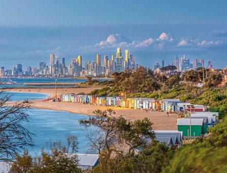 Blick von einem Felsenplateau auf einen tiefblauen Fjord, umgeben von bewaldeten Bergen unter blauem Himmel mit Wolken.