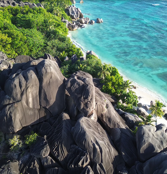 Warmer Winterurlaub: Ein weißer Strand am türkis-blauen Meer mit riesigen Steinen