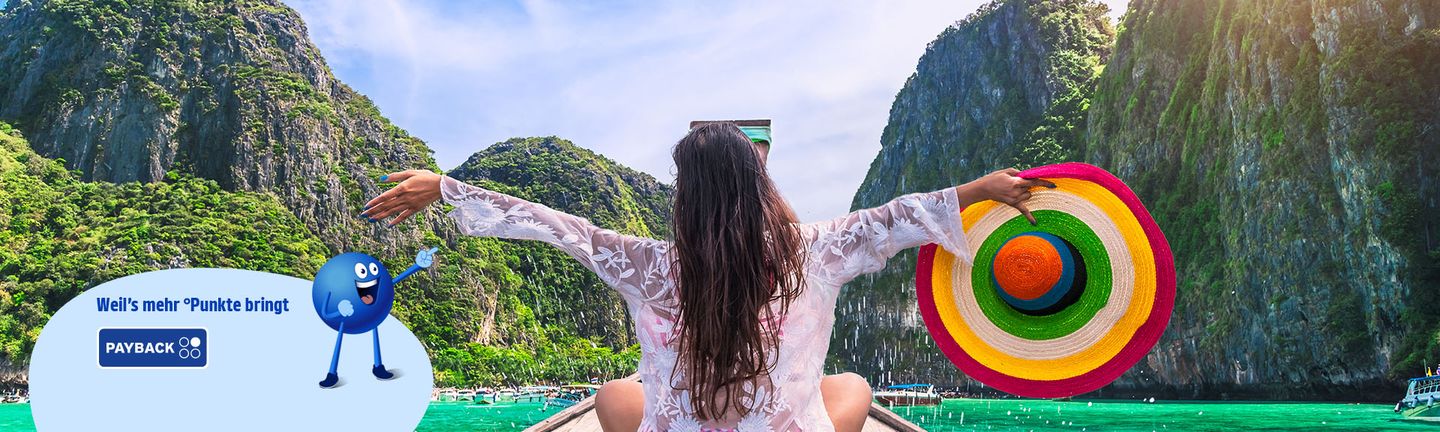 Eine brünette Frau sitzt auf einem thailändischen Longtailboot und reist die Arme auseinander
