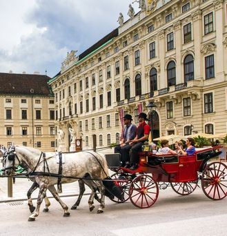 Die typische, wienerische Fiaker (Kutsche) mit zwei weißen Pferden fährt durch die Stadt.