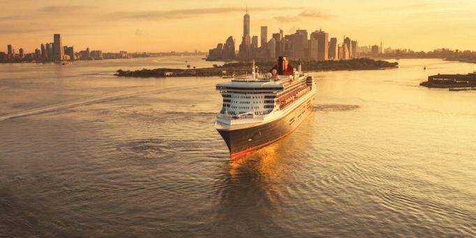 Ein weißes Kreuzfahrtschiff gleitet auf dem Hudson River vor der Skyline von New York, im gelben Sonnenlicht 